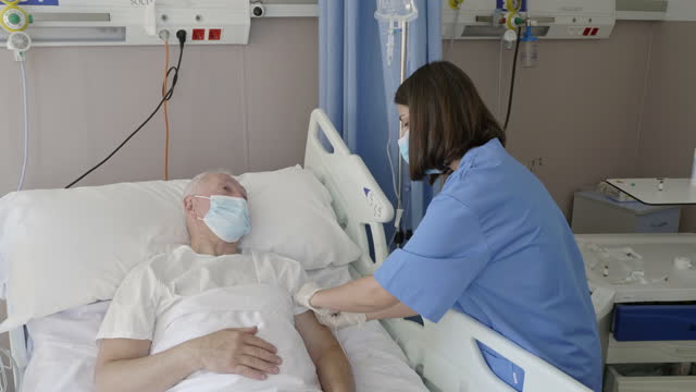 Nurse connecting an IV drip to senior patient