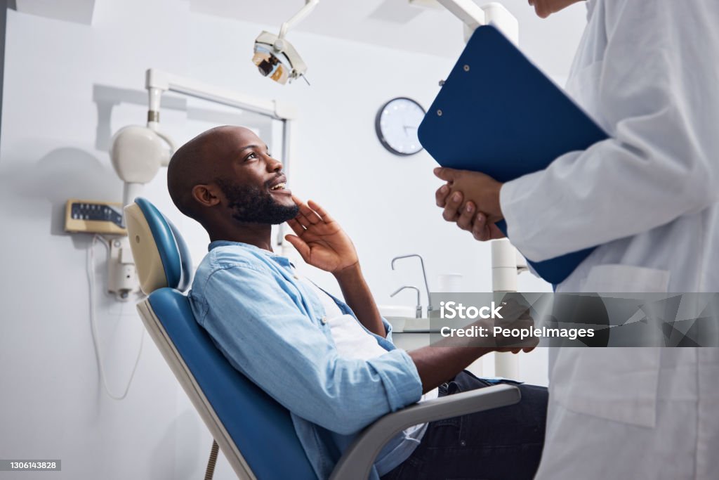 I can already feel the difference Shot of a young man having a consultation with his dentist Dentist Stock Photo
