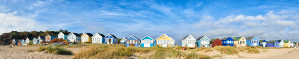The colourful beach huts of Paignton waterside. The photograph was taken at a low angle capturing foreground grass, and showing the huts at a square on angle.