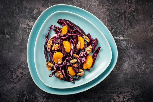 Overhead view of a salad made of; lightly steamed red cabbage with sliced mandarin oranges and walnuts. Colour, horizontal with some copy space.