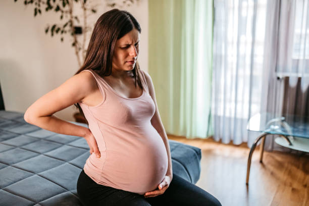 junge schwangere leidet unter rückenschmerzen - muscular contraction stock-fotos und bilder