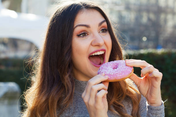 istock Young woman eating a donut 1306146826