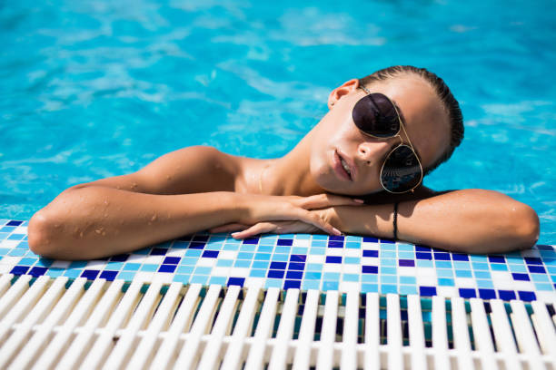 istock Beautiful young woman in bikini at a pool 1306147972