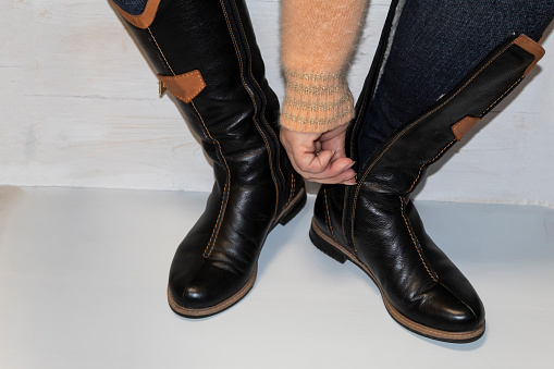 The woman puts on warm leather boots
