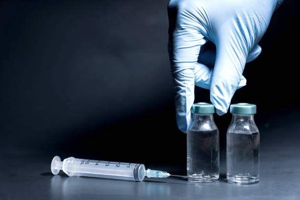 istock Potential trials stage concept on black background. Close up Vials with sterile needle syringe. Research and Development, Vaccination 1306153831