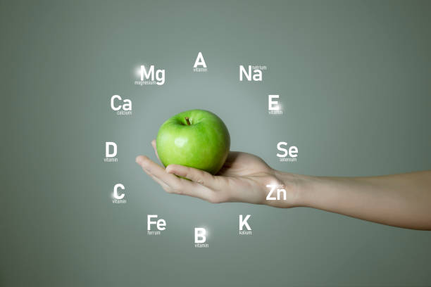 istock Woman`s hand holding green apple, microelement icons in clockface cirlce shape on grey background. 1306155293