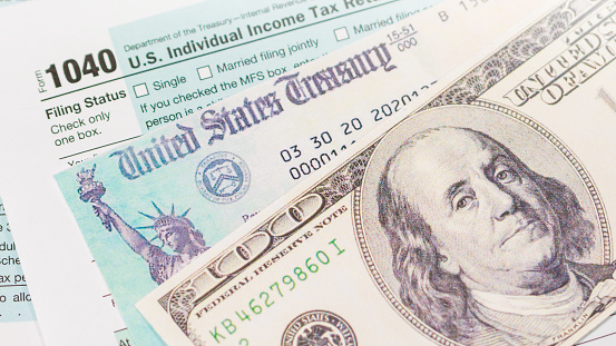 Stimulus economic tax return check and and 1040 Form with dollars.