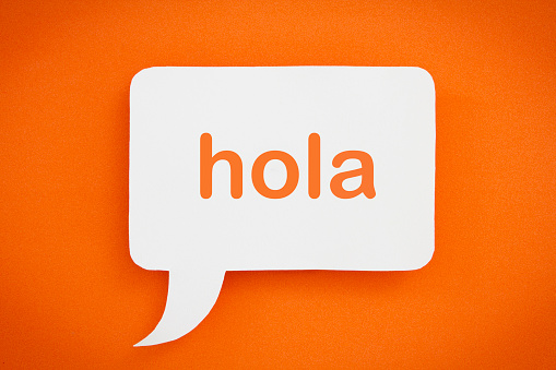 Hola written in a speech bubble, on an orange background.