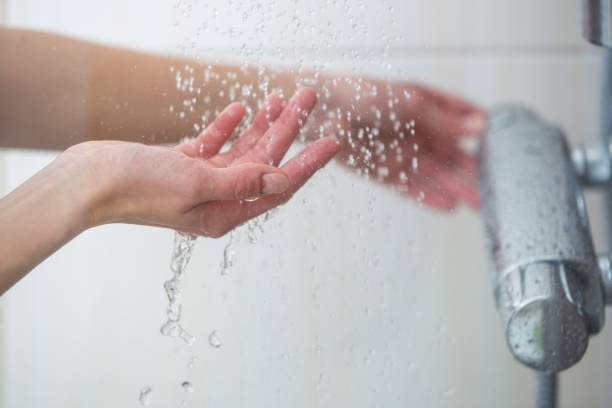 les mains femelles tryimg la température de l’eau dans la douche - shower photos et images de collection