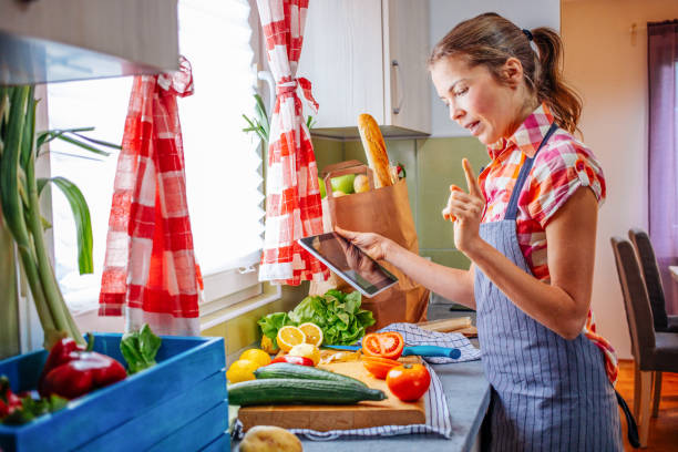 istock Young smiling woman cooking and using tablet. 1306157998