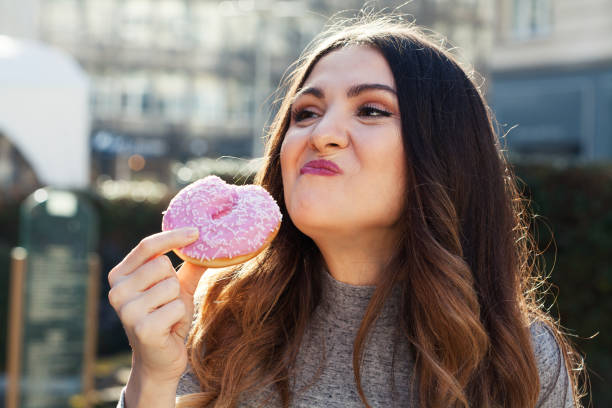 istock Young woman eating a donut 1306158578