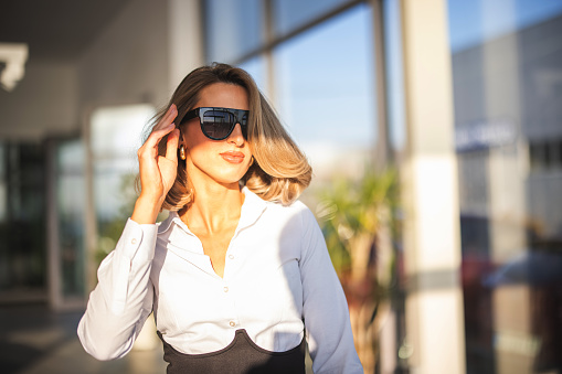 Young well dressed woman with sunglasses leaving car dealership