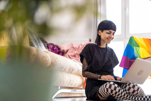 Happy non-binary person using laptop at home Happy non-binary person using laptop at home non binary gender stock pictures, royalty-free photos & images