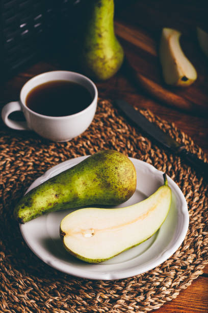 Halved Conference Pear on White Plate and Cup of Coffee