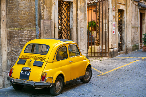 A model of Fiat 500 from the year 1969 parked in an alley in the historic center of Rome, in the Spanish Steps quarter. This vintage car its a symbol of Italian design and industry also present in the MoMA museum of New York. Image in High Definition format.