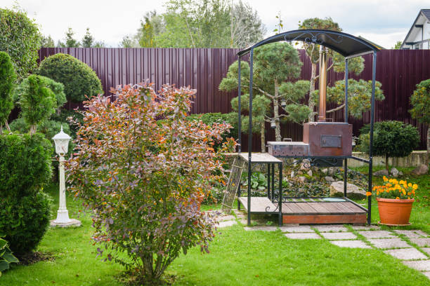 beautiful country house, garden with ornamental trees and plants, flat lawn and landscaping. Garden trees and evergreen conifers. barbecue grill in the garden