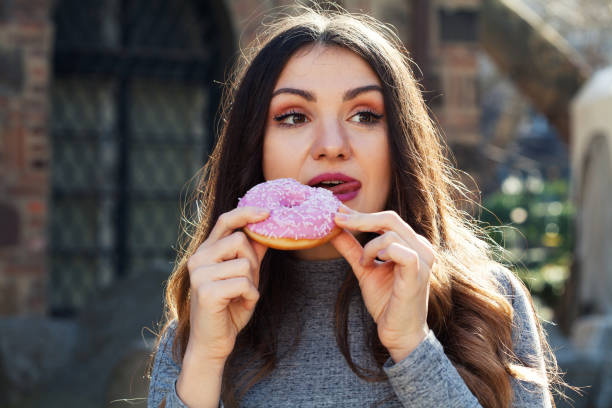 istock Young woman eating a donut 1306168123