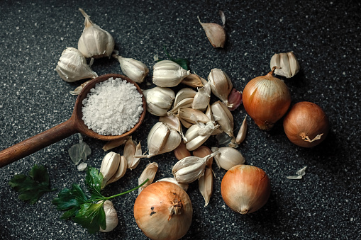 On the kitchen table, a composition of garlic onion and salt is large.