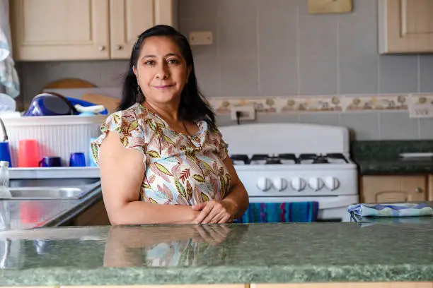 Photo of Proud Hispanic woman posing in her kitchen clean-smiling mom standing in the kitchen-woman in the kitchen not cooking