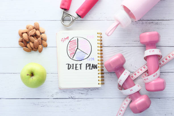 istock Diet plan with apple and dumbbell on pink background 1306175787