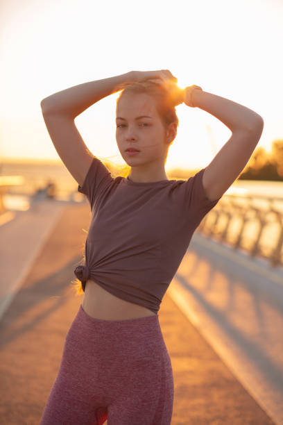 Beautiful ginger woman with athletic body wears sport apparel posing at the bridge
