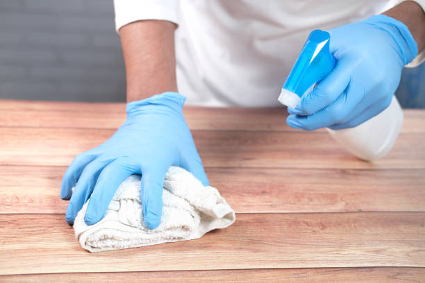 istock hand in disposable gloves using disinfectant spray to clean table surface 1306178535