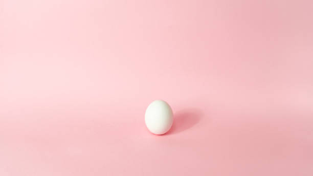 istock One white chicken egg isolated on light pink pastel background. Happy Easter Day. Greeting card. 1306180053