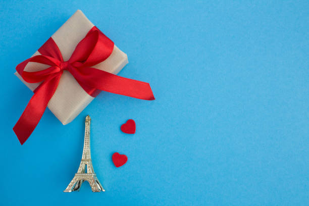 istock Gift with red bow,two small red hearts and eiffel tower souvenir on the blue background 1306180212