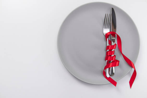 istock Festive table setting with red ribbon. Fork and knife on a gray plate and card postcard for text. Copy space. 1306182633