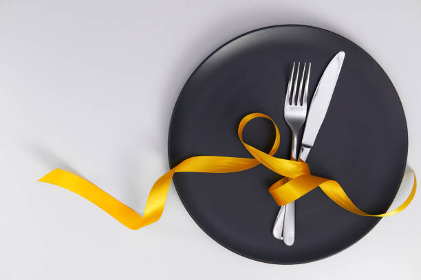 Table setting with gray plate and ribbon. Fork and knife for a holiday dinner on a holiday date. Place for taeksta on a white background.