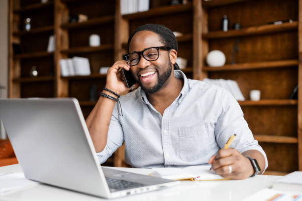 istock An African-American guy using a laptop and has phone conversation 1306184180