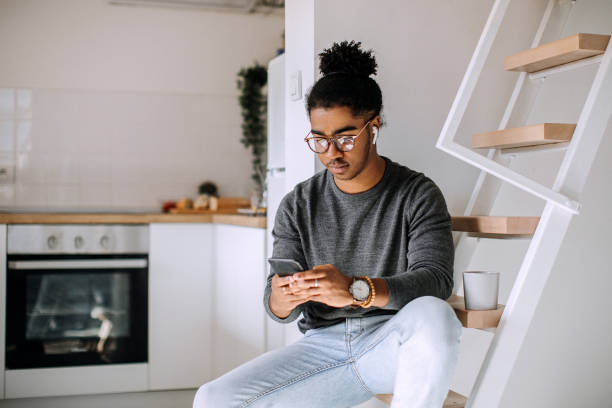 istock Young man texting from mobile phone in his apartment 1306185041