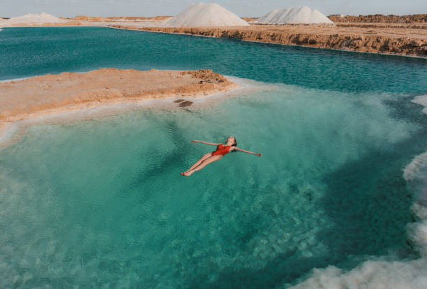 mujer nadando en lago salado en oasis de siwa - egypt fotografías e imágenes de stock