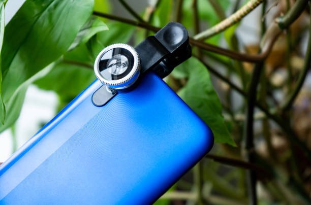 istock Overhead phone lens with clips on the blue modern smartphone. Extra macro camera for mobile device 1306186718