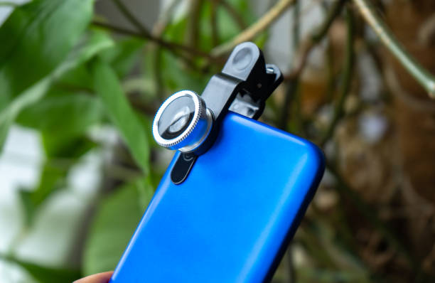 istock Overhead phone lens with clips on the blue modern smartphone. Extra macro camera for mobile device 1306186734