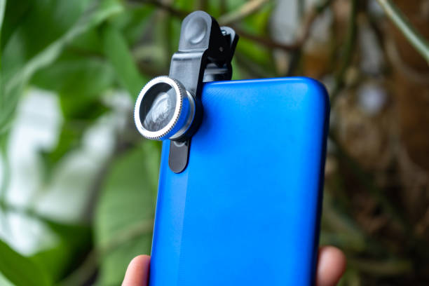 istock Overhead phone lens with clips on the blue modern smartphone. Extra macro camera for mobile device 1306186743