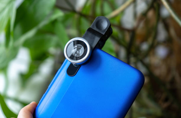 istock Overhead phone lens with clips on the blue modern smartphone. Extra macro camera for mobile device 1306186744