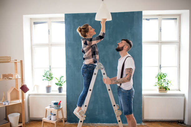 coppia di adulti medio che cambia lampadina al chiuso a casa, trasferimento e concetto fai-da-te. - decorare foto e immagini stock