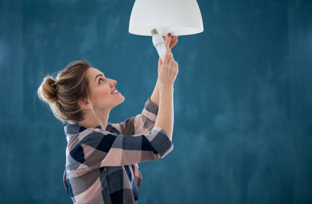 mulher feliz trocando lâmpada dentro de casa, realocação e conceito diy. - changing lightbulb - fotografias e filmes do acervo