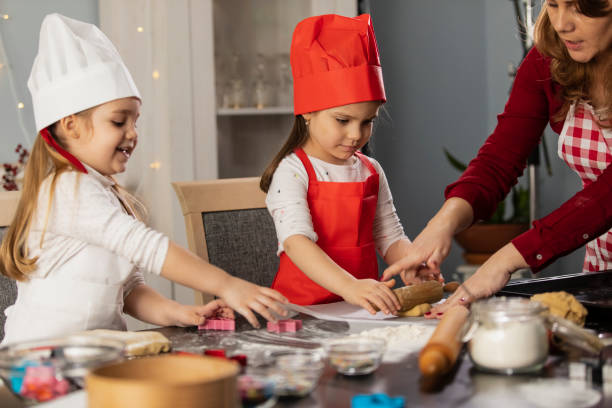 istock Woman assisting her two little daughters in preparing the gingerbread cookie dough 1306189029