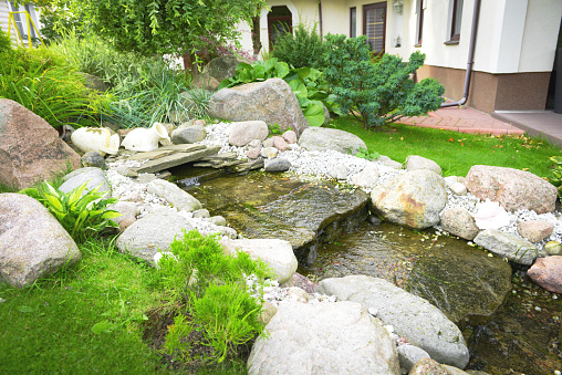 Magical quiet and relaxing green lush gardens behind cutes gates with fountains, rock path to gazebo and and plants of all varieties.