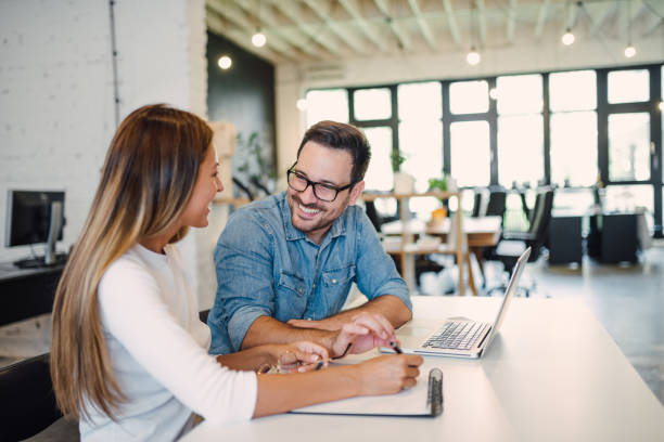 istock Two cheerful colleagues smiling while discussing something in modern office. 1306189467
