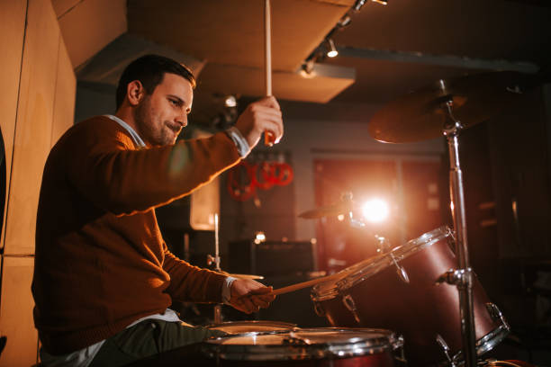 istock Playing drums and having fun. Portrait of a man playing drums, side view. 1306189794