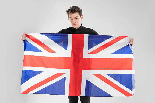 Portrait of adult caucasian man with national British flag at the studio. Concept with gray background and copy space