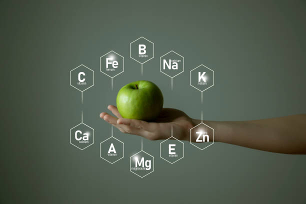 istock Woman`s hand holding green apple, microelement icons in molecular hexagons on grey background. 1306192104