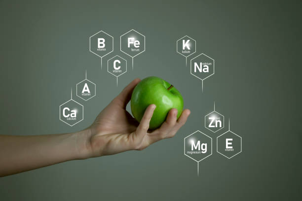istock Woman`s hand holding green apple, microelement icons in molecular hexagons on grey background. 1306192275
