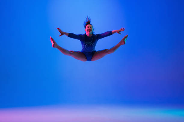 istock Young flexible girl isolated on blue studio background. Young female model practicing artistic gymnastics. Exercises for flexibility, balance. 1306193739