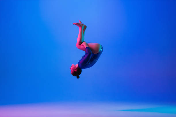 istock Young flexible girl isolated on blue studio background. Young female model practicing artistic gymnastics. Exercises for flexibility, balance. 1306193768