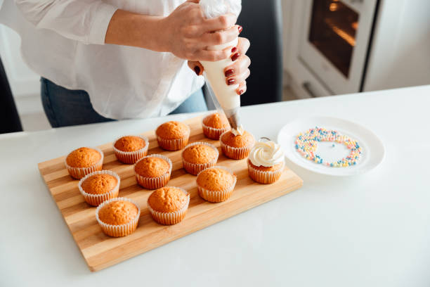 istock Woman decorates freshly baked cupcakes with cream 1306194379