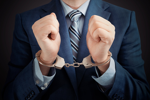 Businessman arrested for corruption. Man in a suit with handcuffs on his hands